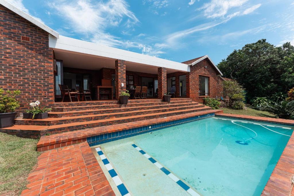 a brick house with a swimming pool and stairs at The Milkwood Beach House in Zinkwazi Beach