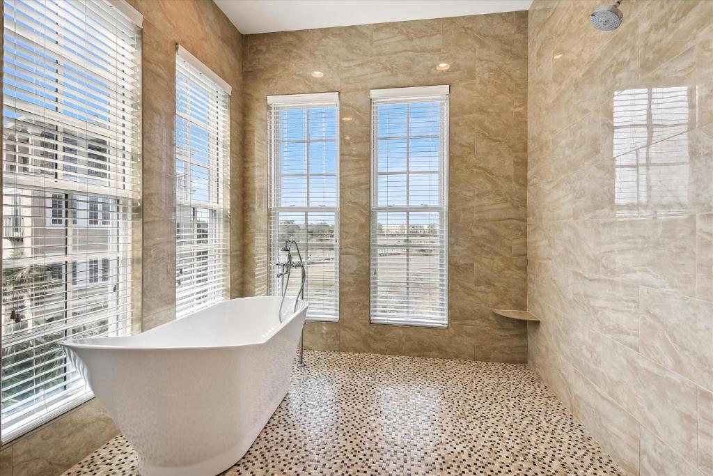 a bathroom with a white tub and windows at 27 Singleton Beach- Oceanfront, Private Pool, Pool Table, FREE Activities Included in Hilton Head Island