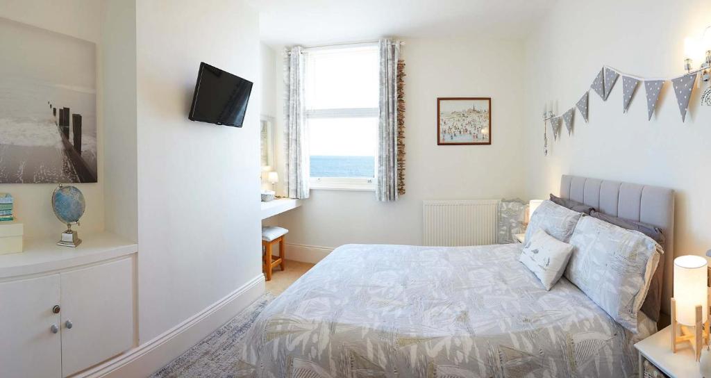 Un dormitorio con una cama con televisión y una ventana. en Apartment 17, The Moorings - Stunning sea views, en Filey