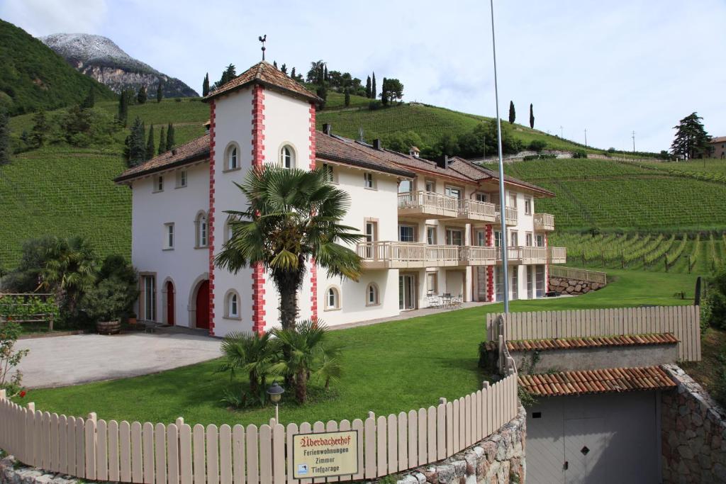 a large white house with a palm tree in front of it at Überbacherhof in Termeno