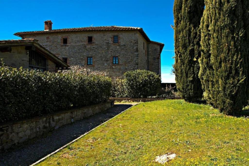 een groot stenen gebouw met een gazon ervoor bij Chianti House in Gaiole in Chianti