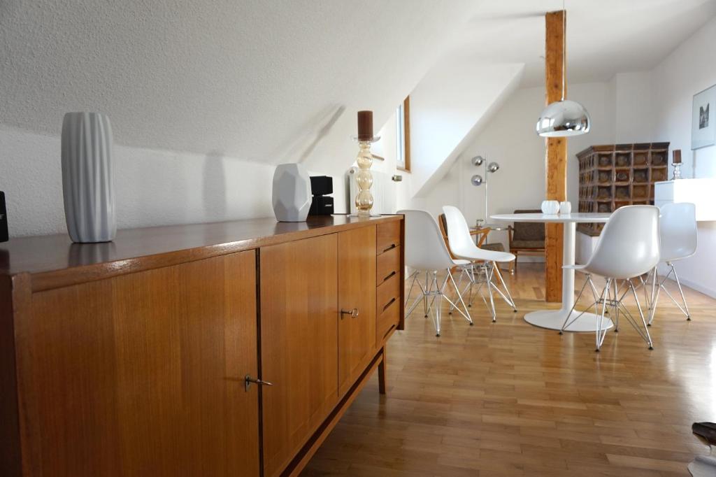 a kitchen with a large wooden cabinet and white chairs at Apartments 11 in Forchheim