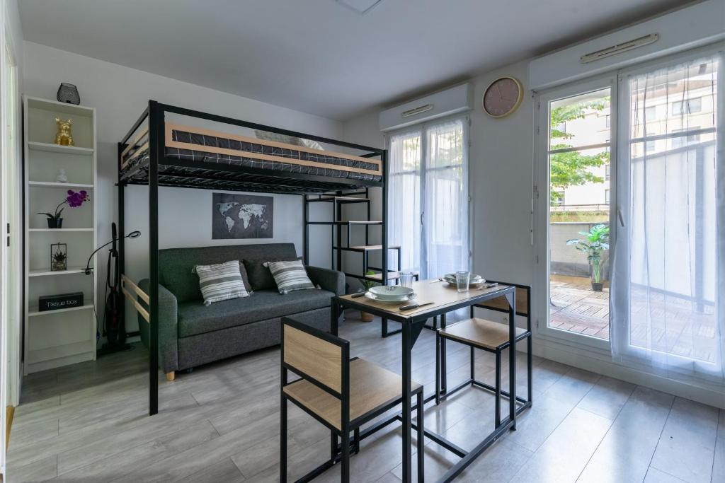 un salon avec un lit et une table dans l'établissement Le Bougainvillier - charmant studio avec balcon, à Bussy-Saint-Georges