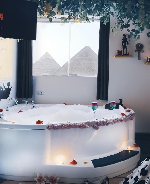 a bath tub with two wine glasses in front of a window at Pyramids ICON 4 & 5 in Cairo