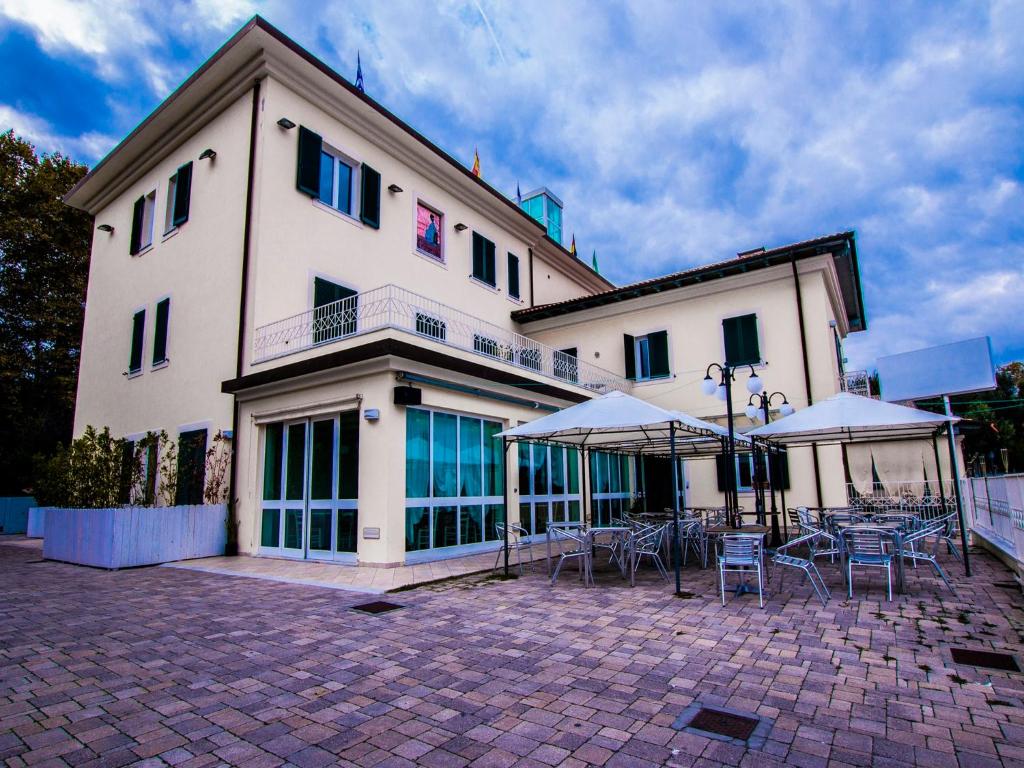 un bâtiment avec des tables et des parasols devant lui dans l'établissement Hotel Butterfly, à Torre del Lago Puccini