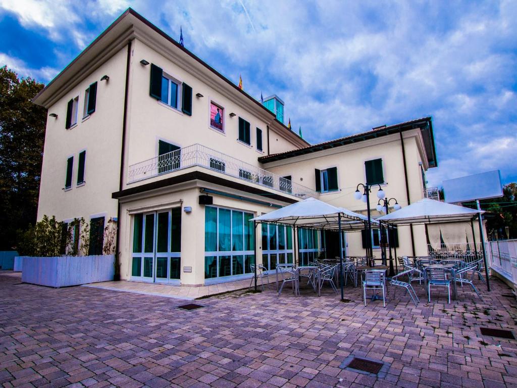 ein Gebäude mit Tischen und Sonnenschirmen davor in der Unterkunft Hotel Butterfly in Torre del Lago Puccini