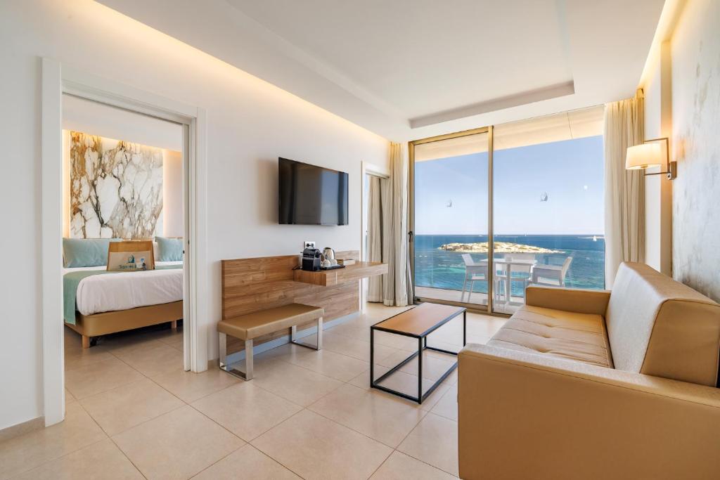 a hotel room with a couch and a bed and a television at Hotel Torre del Mar - Ibiza in Playa d'en Bossa