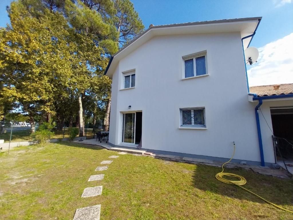 une maison blanche avec un tuyau jaune dans la cour dans l'établissement Villa BIENVENUE, à Andernos-les-Bains