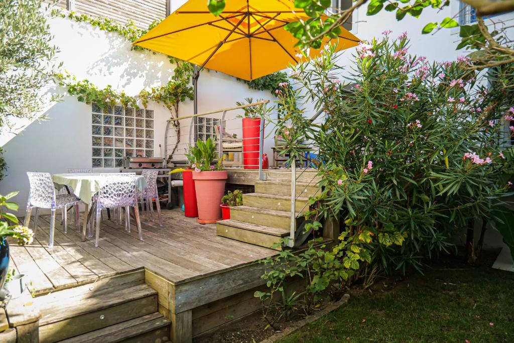 un patio avec une table et un parasol dans l'établissement Jolie maison sablaise avec jardin quartier Arago et proche plage, Les Sables - 8 personnes, à Les Sables-dʼOlonne