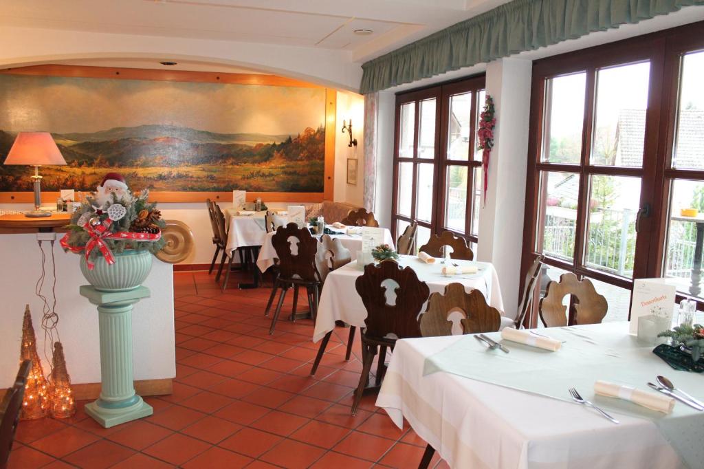 Landgasthof Hotel Zur Linde im Taunus في Gemünden: مطعم بطاولات بيضاء وكراسي ولوحة