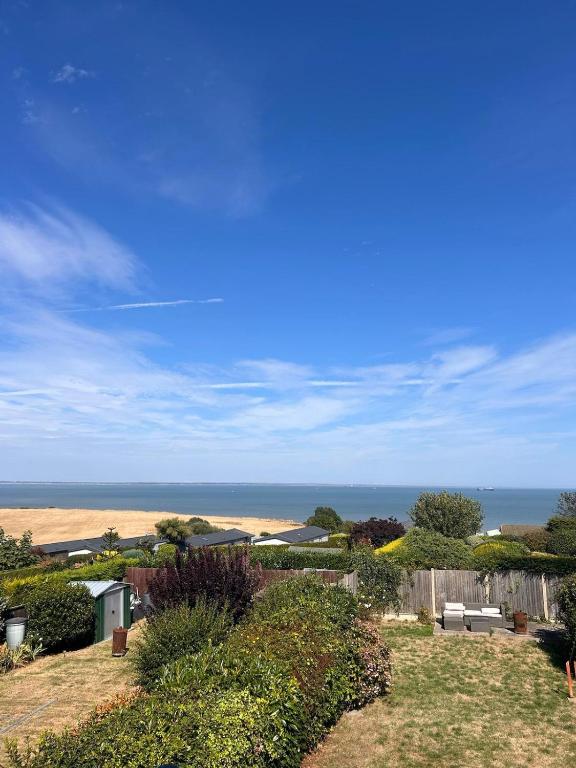 a view of a yard with the ocean in the background at Family & Pet-Friendly Seaside Bungalow with Accessible Features in Minster