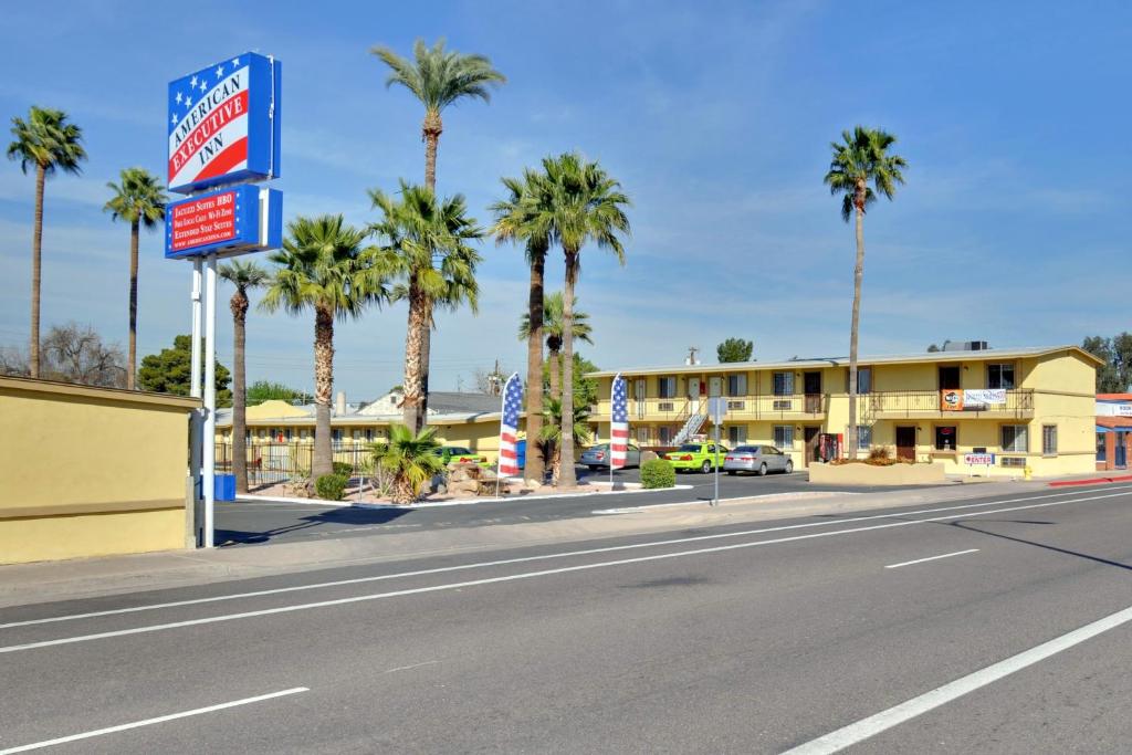 een straat met palmbomen voor een motel bij American Executive Inn Mesa in Mesa