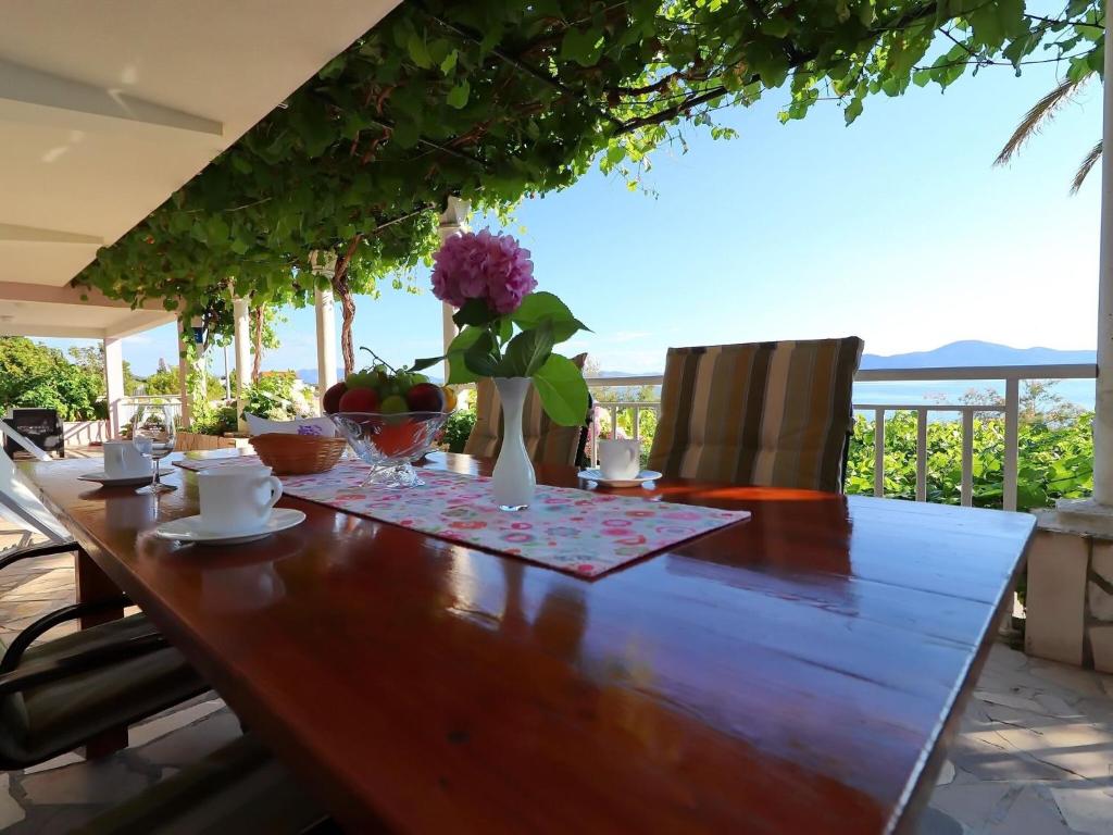 une table en bois avec un vase de fleurs dessus dans l'établissement Apartments Stipo - Comfort One Bedroom Apartment with Terrace and Sea View A1, à Drače