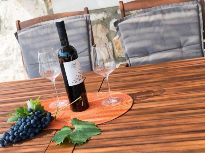 - une bouteille de vin et 2 verres à vin sur une table en bois dans l'établissement Holiday Home Anima Maris- Duplex Two Bedroom Holiday Home with Terrace and Sea View, à Ston