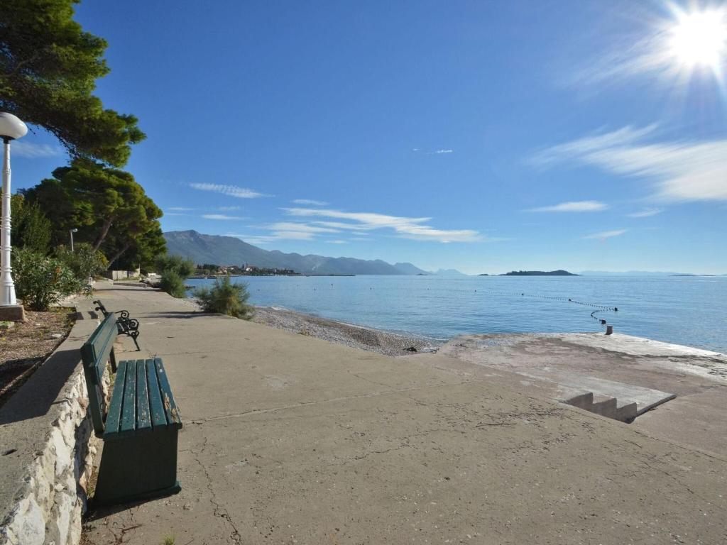a green bench sitting next to a body of water at LaidBack Apartments - Comfort One Bedroom Apartment with Balcony and Sea View Green in Orebić