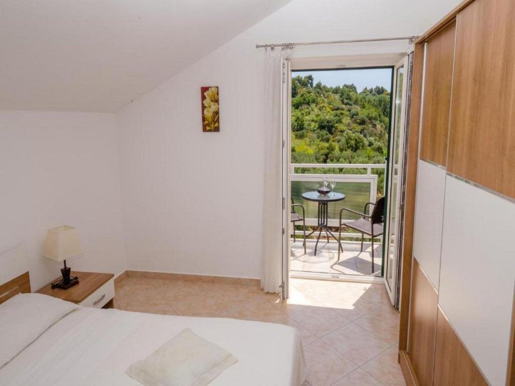 a bedroom with a bed and a balcony with a table at Apartments Bandalo - Standard Studio Apartment in Podstrana