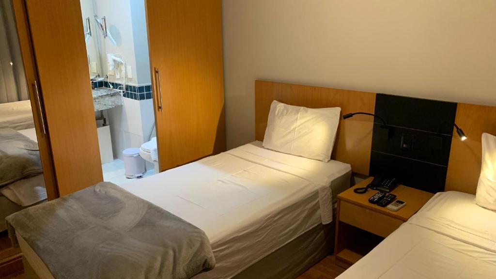 圣保罗Flat confortável próx Ibirapuera e Jardins com garagem的有两张床和一面镜子的小房间