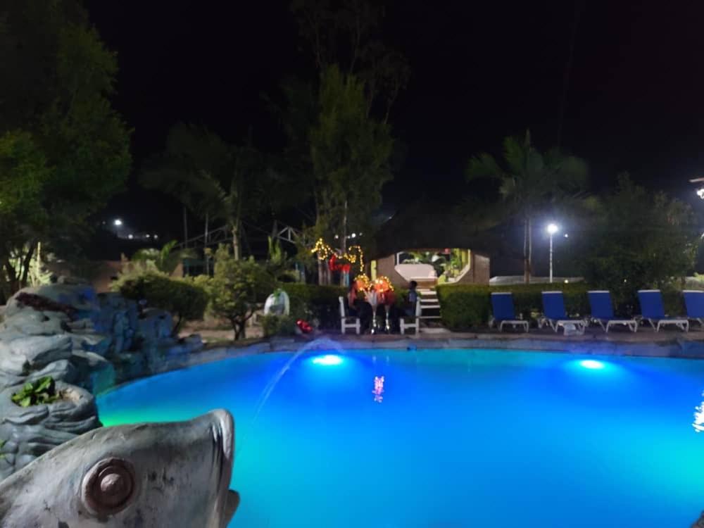 een groot blauw zwembad 's nachts bij Hasna lodge in Ruashi