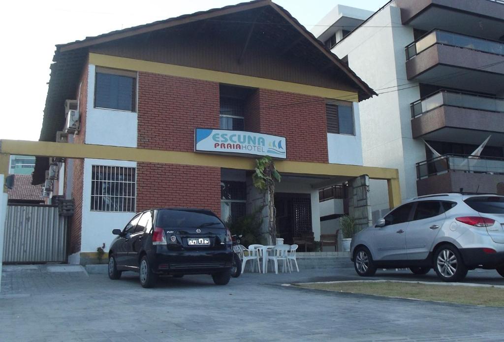 dos autos estacionados en un estacionamiento frente a un edificio en Escuna Praia Hotel, en João Pessoa