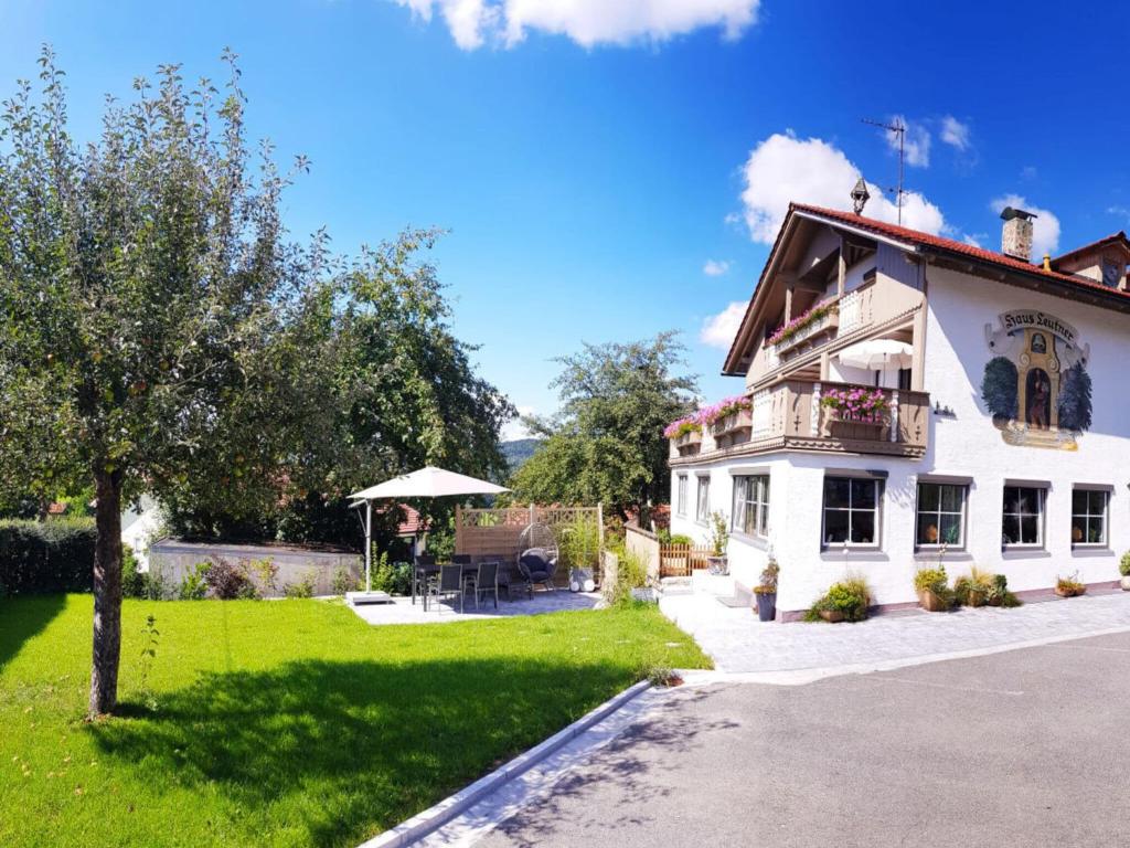 a white house with a balcony and a yard at Holiday apartment Haus Leutner Bavarian Forest in Bodenmais