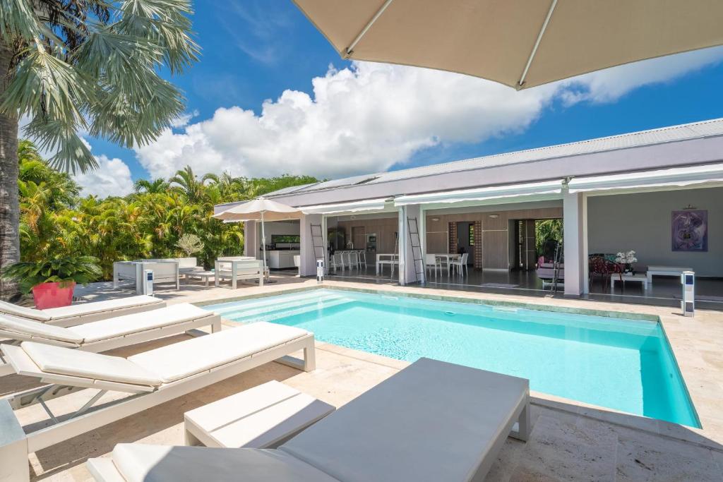 a swimming pool with chairs and a house at Villa Azur in Saint-François