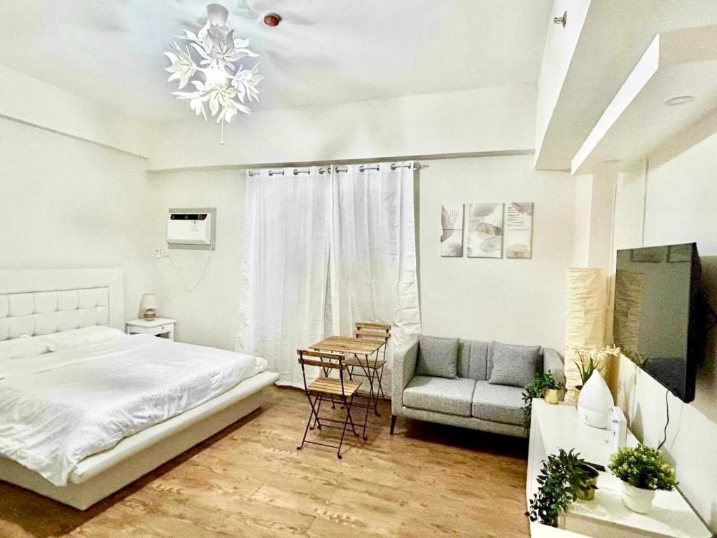 a bedroom with a bed and a chair and a couch at Aloria Cozy Apartment near Mactan Cebu International Airport - Amani Grand Resort & Residence in Pusok