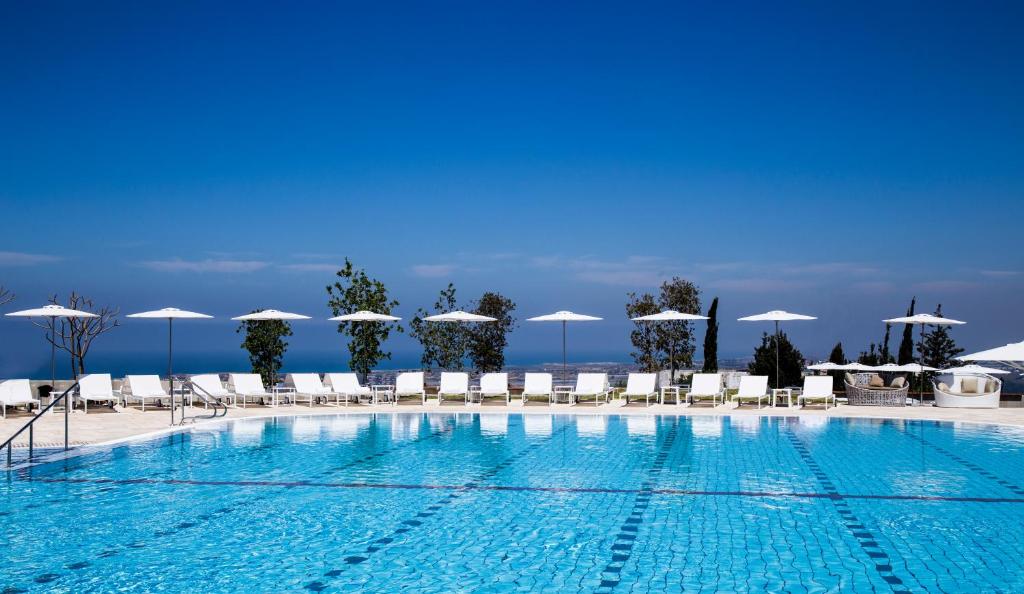 a large swimming pool with chairs and umbrellas at Elma Hotel and Art Complex in Zikhron Ya'akov