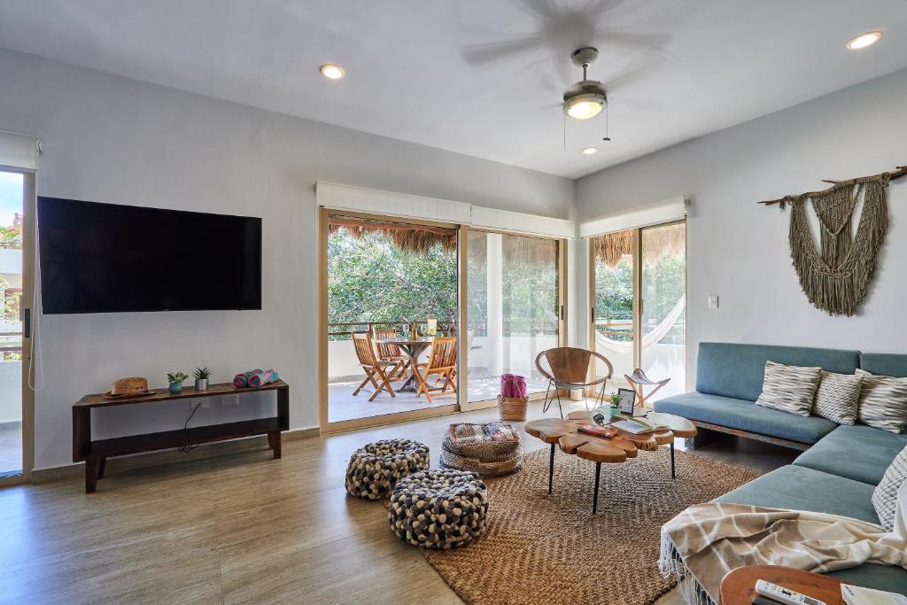 un salon avec un canapé bleu et une télévision dans l'établissement Beautiful Penthouse with Private Rooftop and Hot Tub, à Tulum