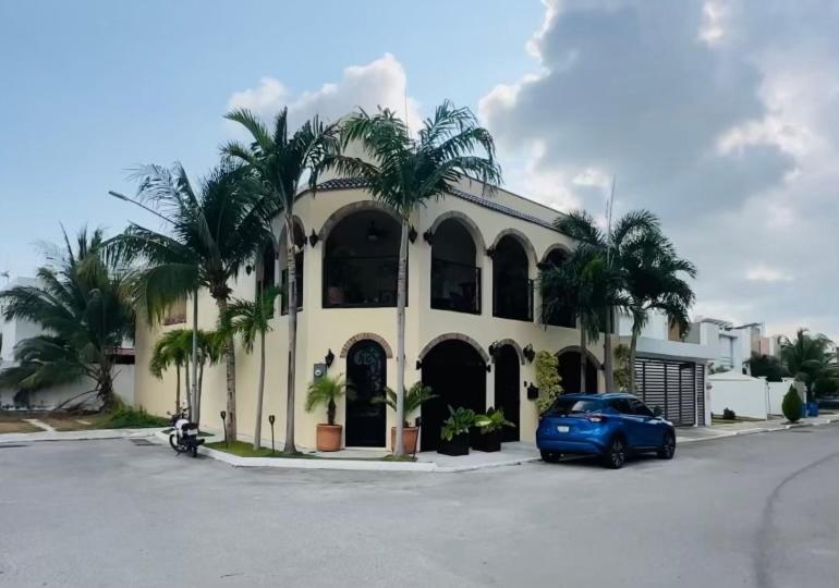 ein blaues Auto, das vor einem Gebäude mit Palmen parkt in der Unterkunft Casa Castillo Playa in Playa del Carmen