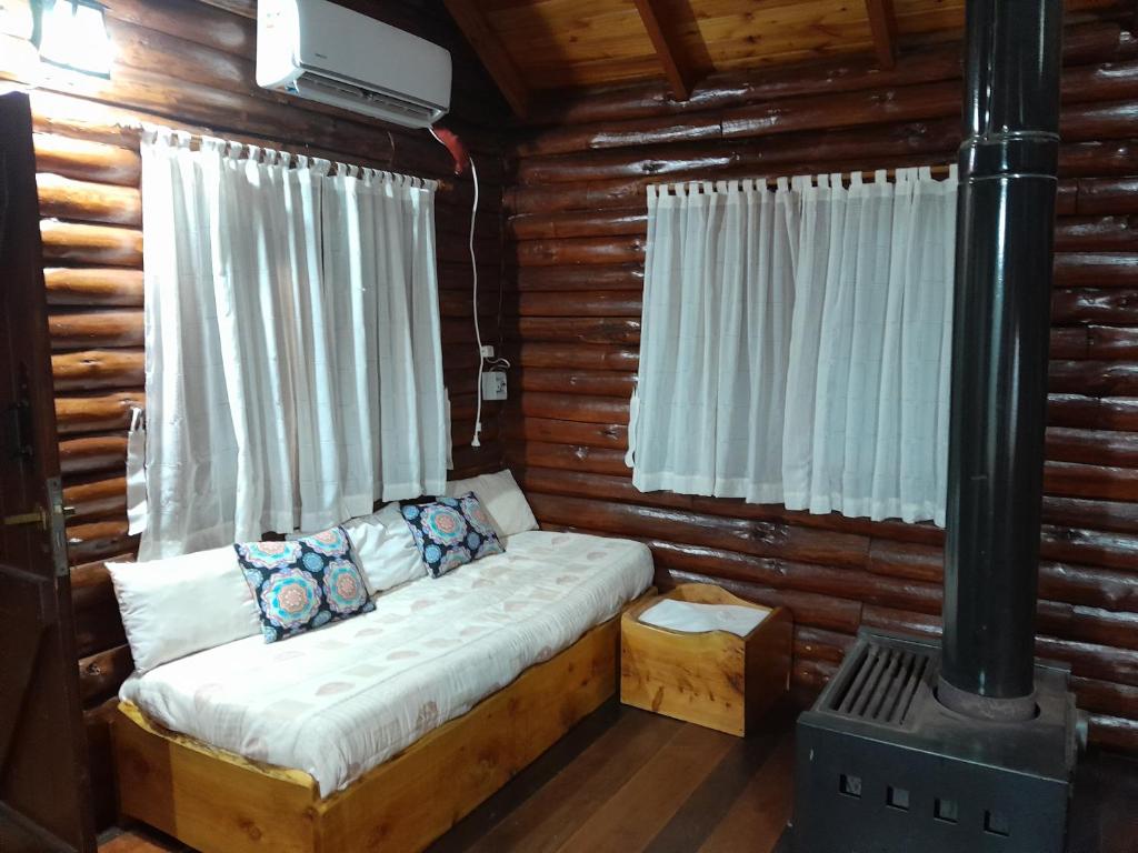 ビジャ・ヘネラル・ベルグラーノにあるAldea Las Calandriasのコンロ付きのログキャビンのベッド1台分です。
