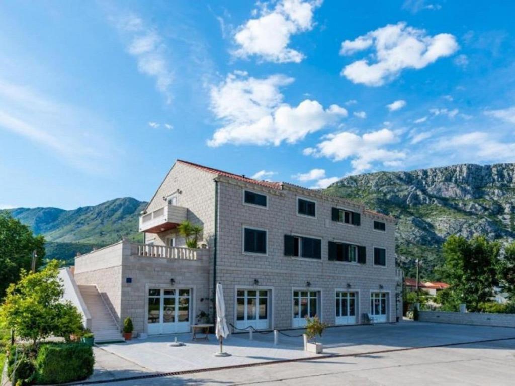 a large white building with mountains in the background at Villa Dubelj Dubrovnik - One-Bedroom Apartment - 2 in Komolac