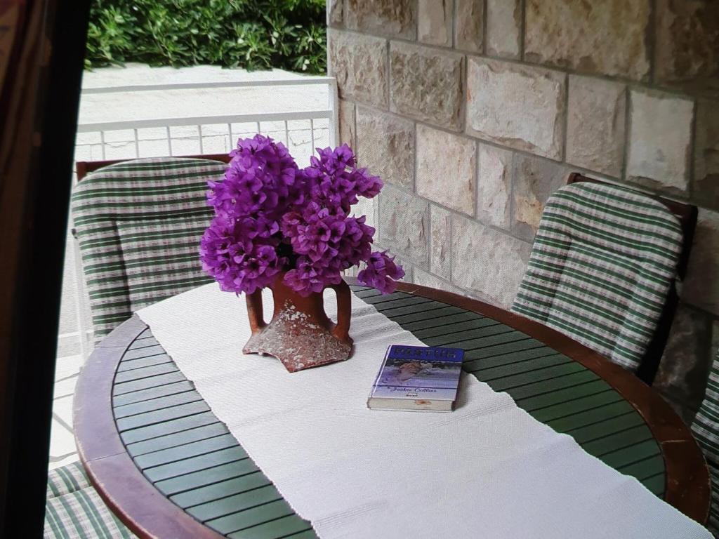 a table with a vase with purple flowers on it at Apartments Maria Kolo ep- Three Bedroom Apartment with Backyard Terrace and Sea View in Koločep