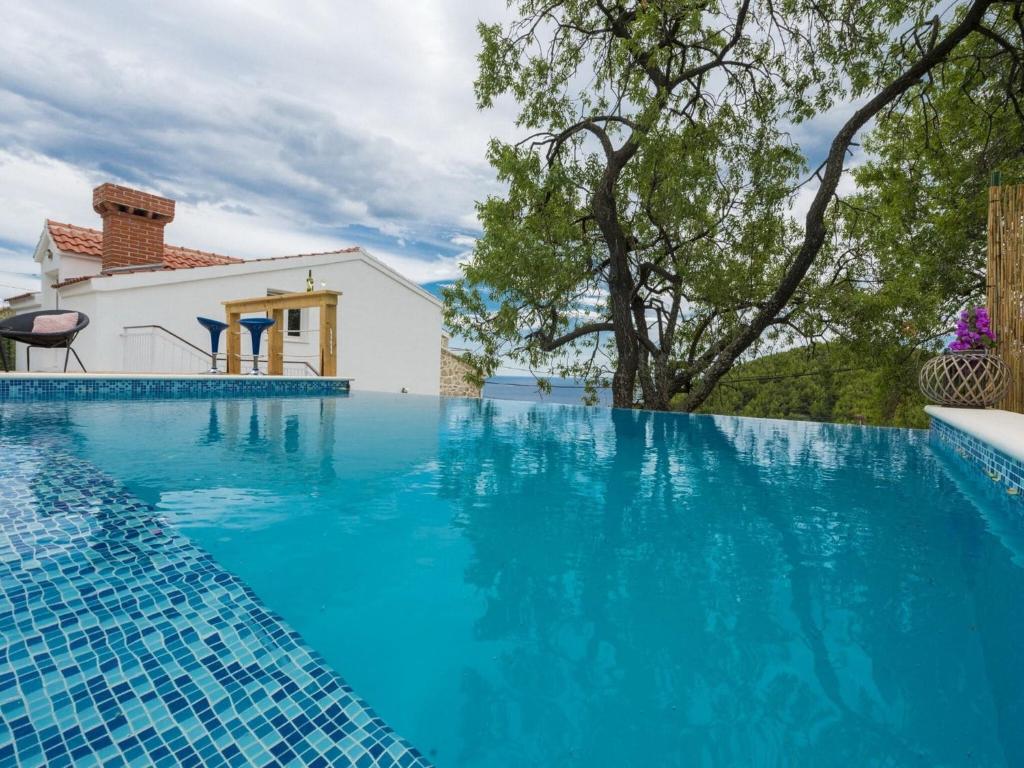 einen Pool mit blauem Wasser vor einem Haus in der Unterkunft Villa Dundo Pero - Four Bedroom Villa with Swimming Pool and Sea View in Babino Polje