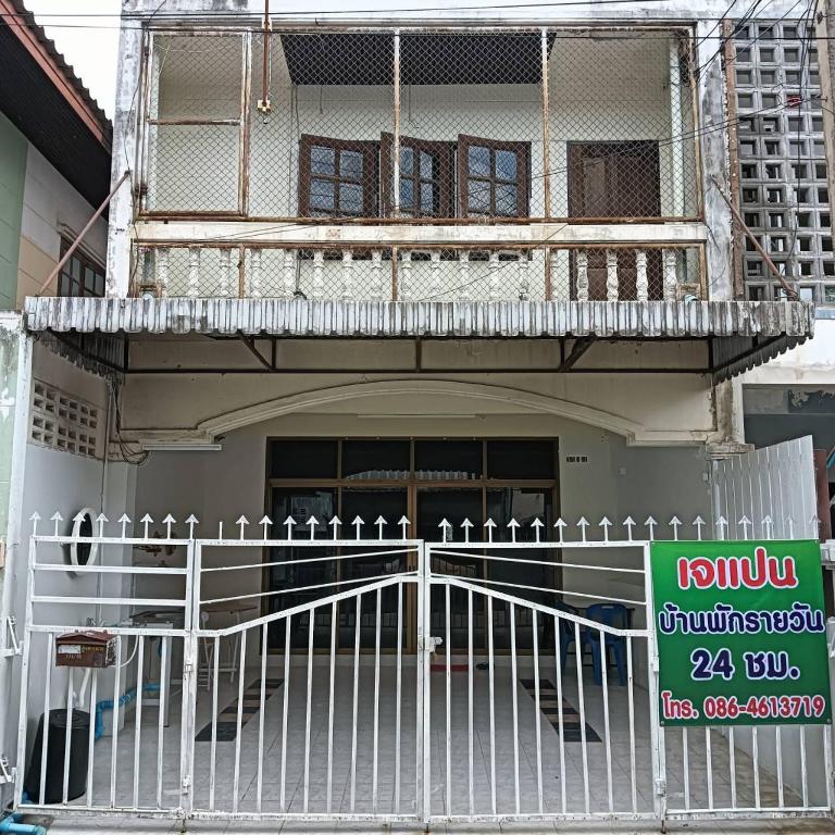 a white fence in front of a building with a balcony at เจแปน บ้านพักรายวัน in Pak Chong