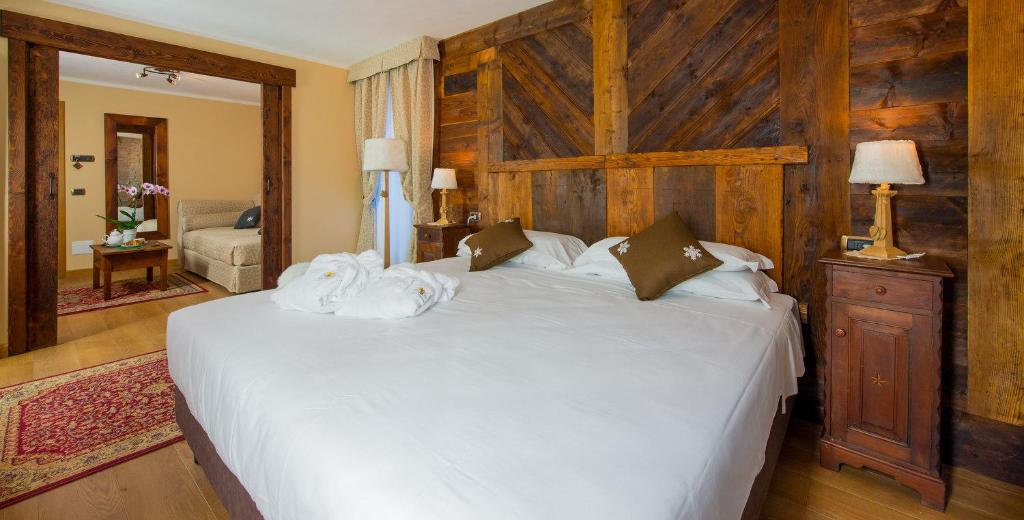 a bedroom with a white bed with a wooden wall at Hotel Edelweiss 3 Stelle SUPERIOR in Breuil-Cervinia