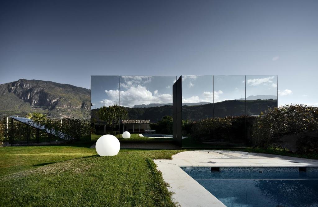 ein Haus mit einem Pool im Gras in der Unterkunft Mirror Houses in Bozen