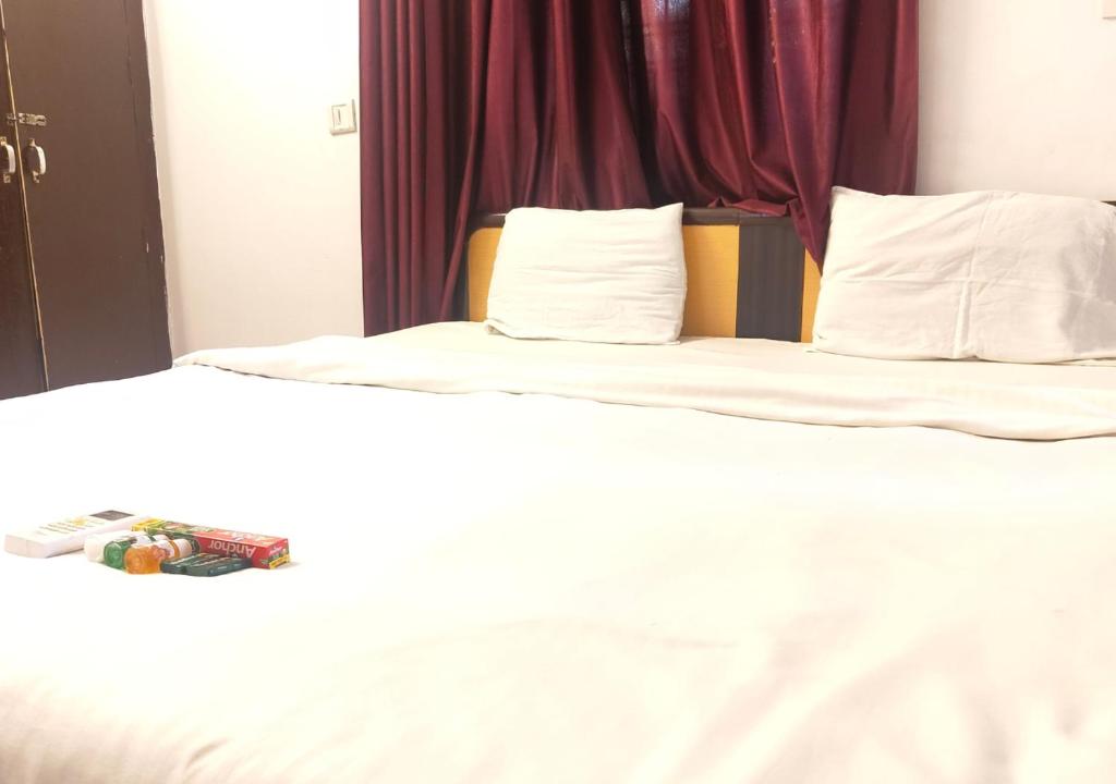 two beds in a hotel room with white sheets at ZoukStayz in Rishīkesh