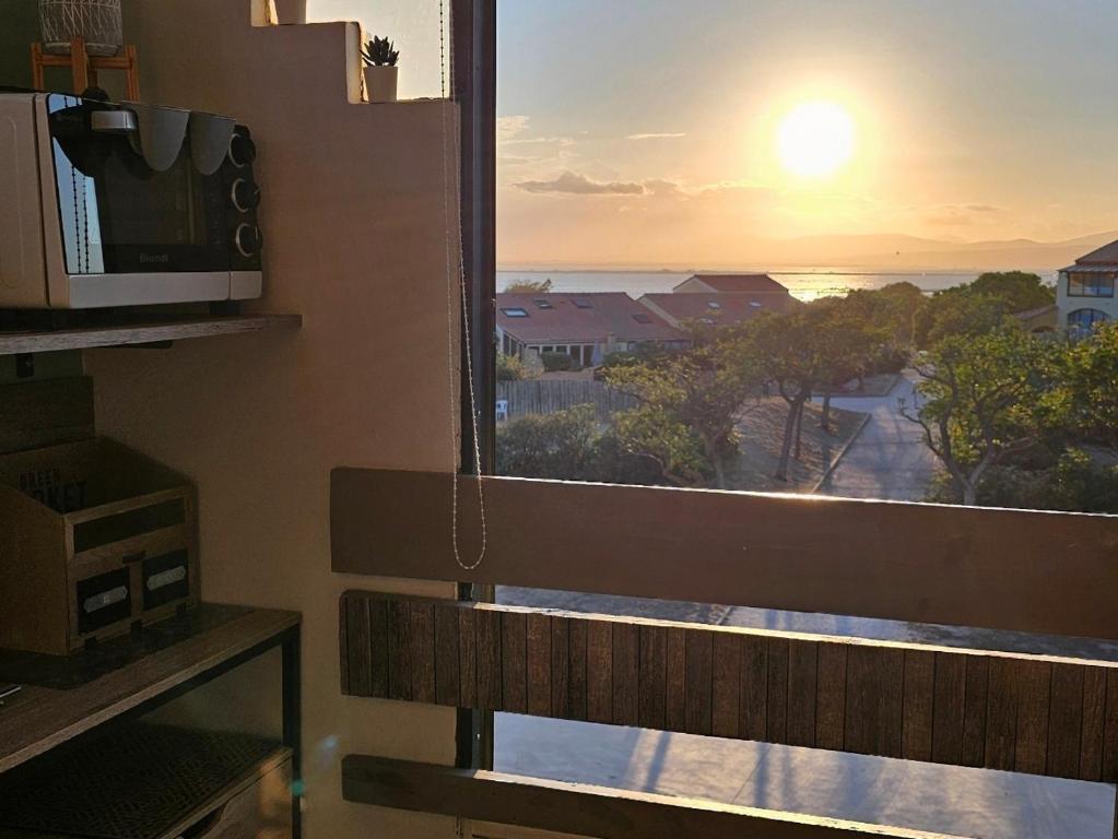 - une vue sur le coucher du soleil depuis une fenêtre dotée d'un banc dans l'établissement T3 vue époustouflante proche plage parking Wi-Fi gratuit, au Barcarès