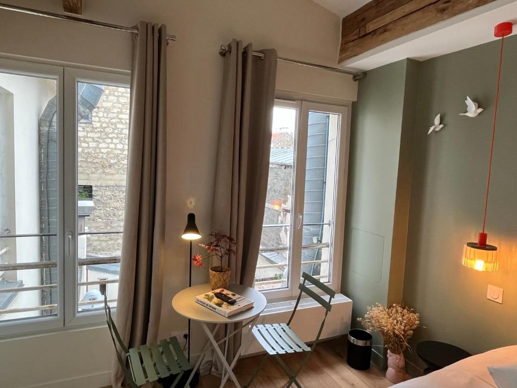 une petite table dans une pièce avec une fenêtre dans l'établissement Saint Jacques Luxembourg, à Paris
