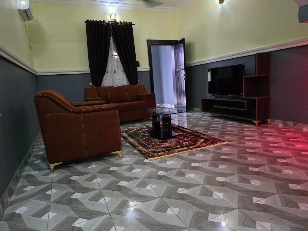 un salon avec un canapé et une télévision dans l'établissement Edna Apartments, à Aba