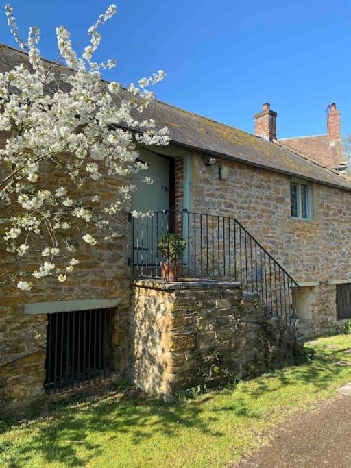 a brick house with a gate and a flowering tree at The Granary, Barwick in Yeovil