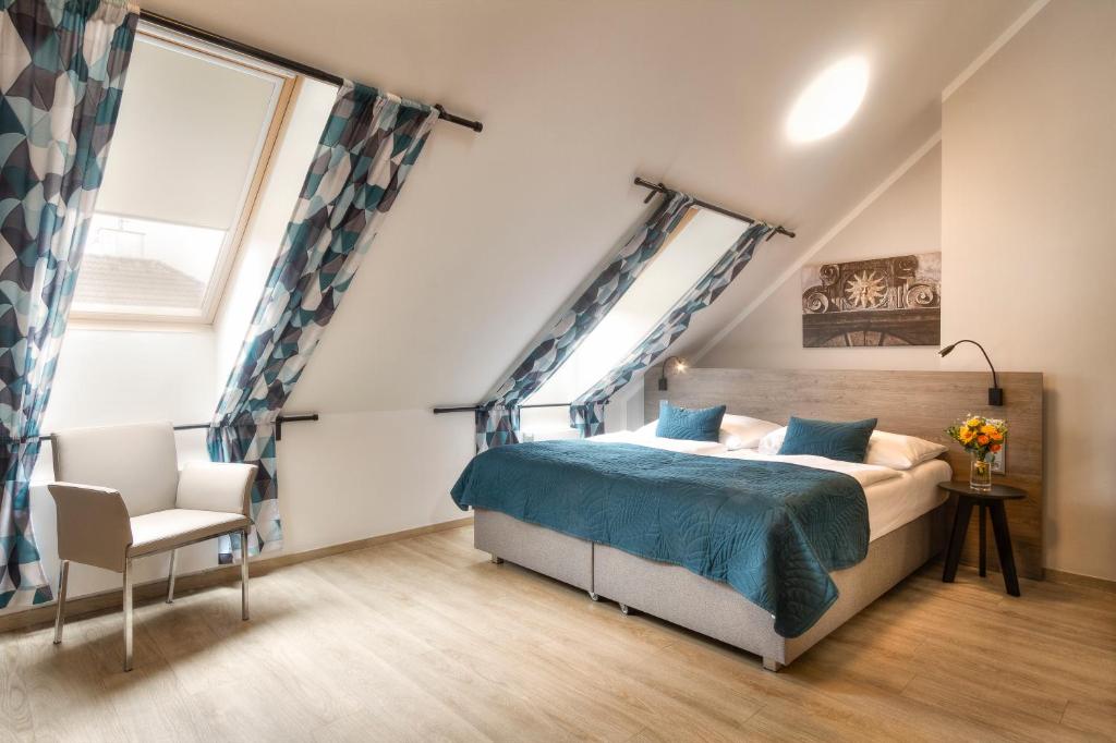 a bedroom with a large bed and a chair at Hotel Páv in Prague