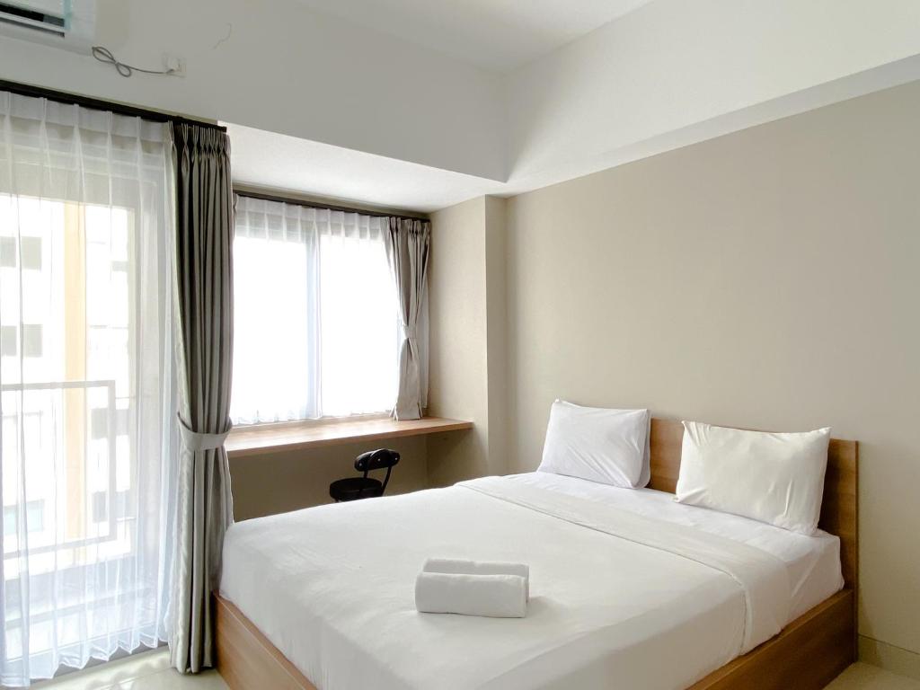 a bedroom with a white bed with a box on it at Good Choice and Cozy Studio Gateway Park LRT City Jatibening Apartment By Travelio in Bekasi