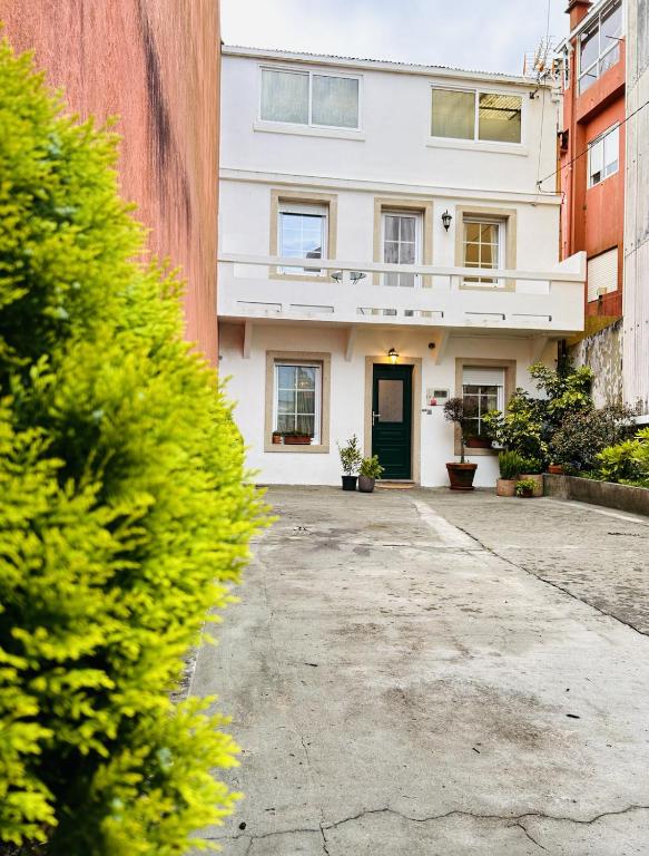 a white building with a green door in a courtyard at Casa Casco Antiguo A Guarda in A Guarda