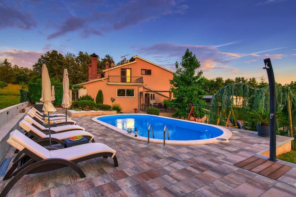 a backyard with a swimming pool with chairs and umbrellas at Villa Mikela Heki, Pazin by IstriaLux in Heki