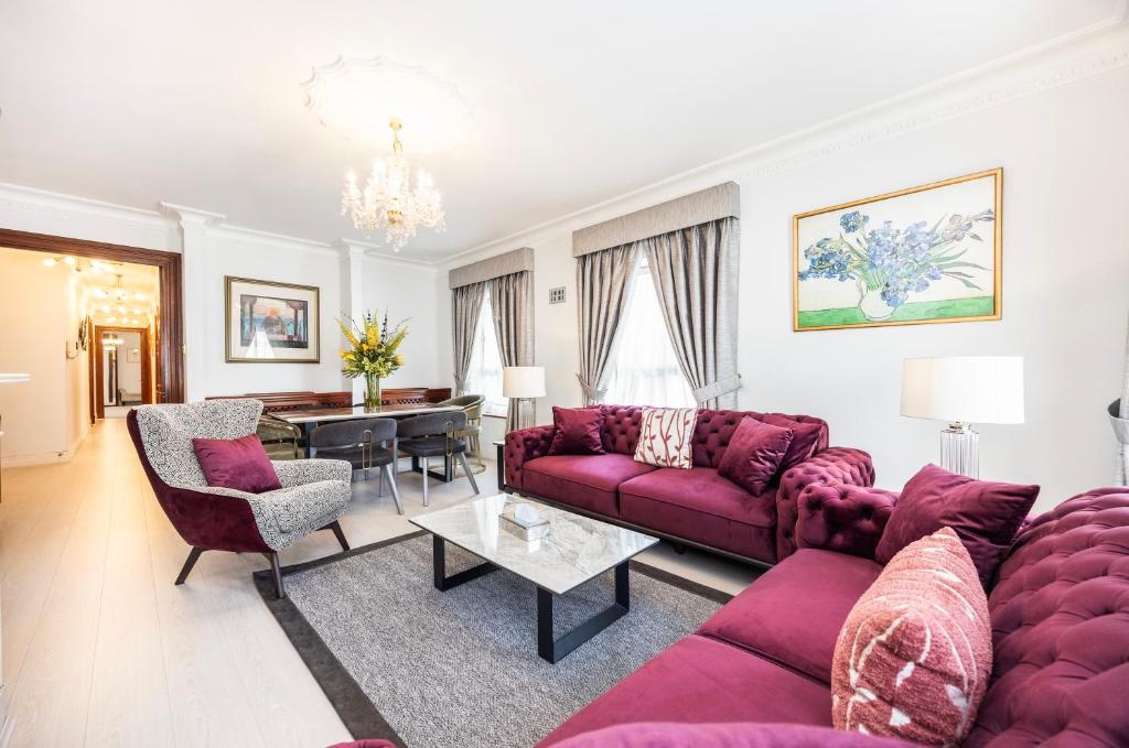 een woonkamer met paarse banken en een tafel bij CARLTON COURT - MAYFAIR in Londen