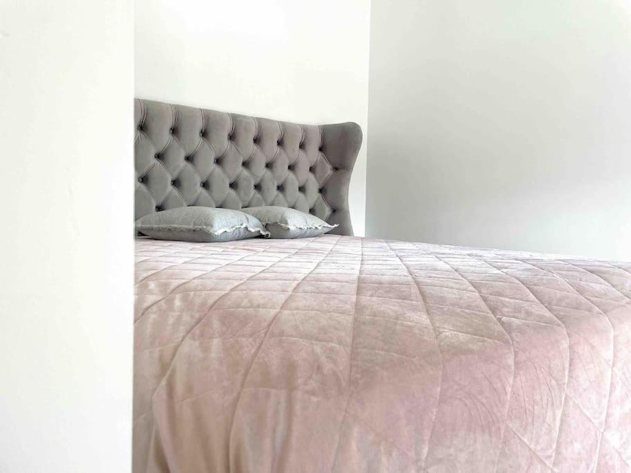 een bed met een roze deken en kussens erop bij Uliha street sea side apartment in Liepāja