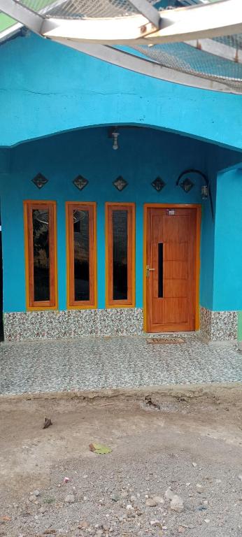 a blue building with a wooden door and windows at Cena Homestay in Rejeng