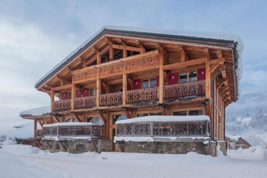 une cabane en rondins dans la neige avec un balcon dans l'établissement Chalet Grand Mouflon, aux Gets