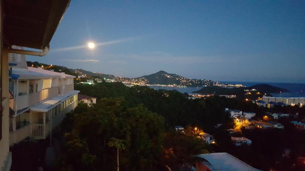 a view of a city at night with the moon at Sunset Gardens Guesthouse in Charlotte Amalie